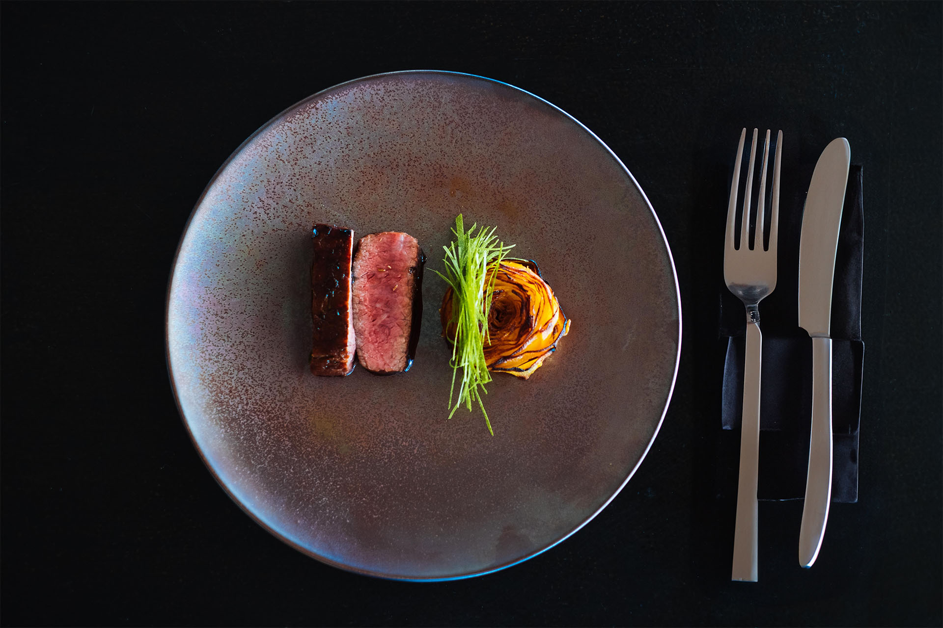 Wildfleisch Steak auf dem Teller mit Beilage und Besteck daneben